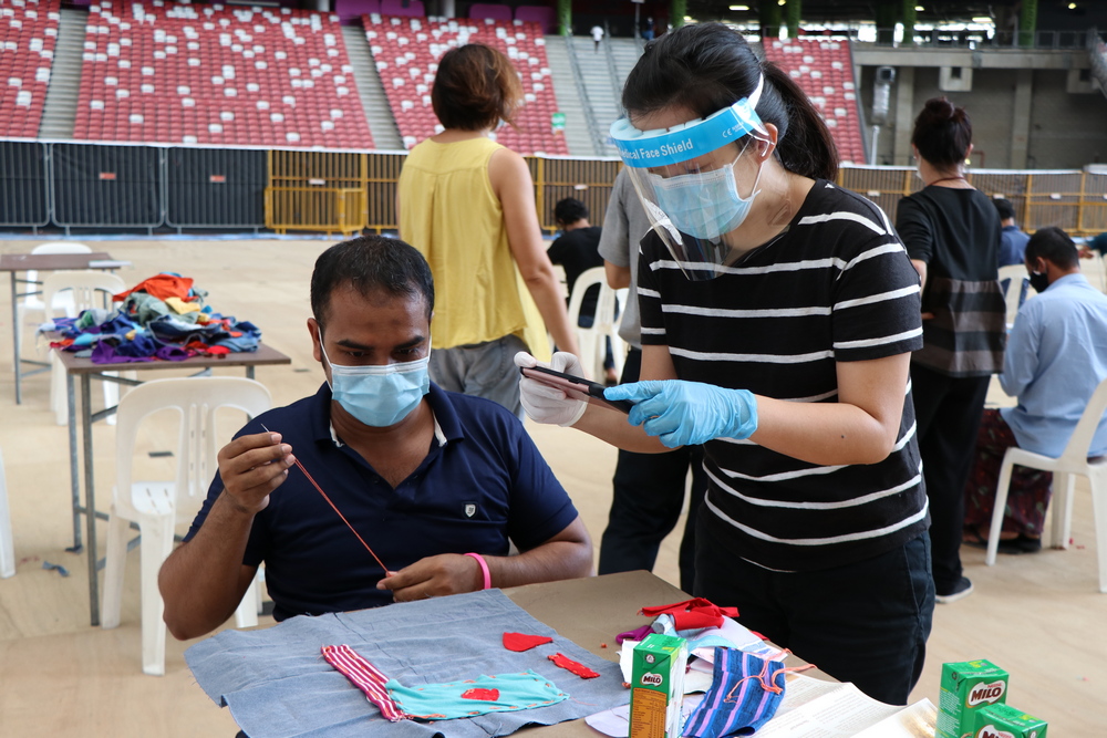 新加坡国际基金会代表黄小姐(右)抽空与客工一起参与缝纫。 摄 / 连雅慧