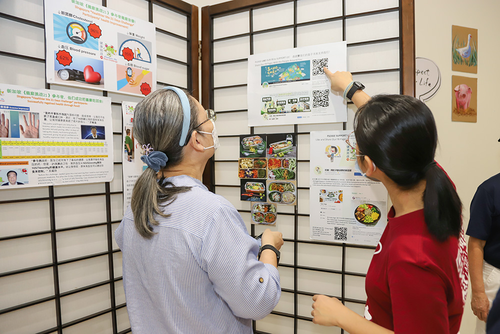 At the “Healthier Me 21-Day Challenge” exhibition zone, volunteers share the results and data collected from the challenge for the public to have a better understanding of how a plant-based diet can improve their health. (Photo by Chua Teong Seng)