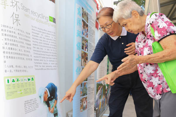 志工黄碹意引领吴亚容阿嬷(右)到看板区,仔细地为她讲解全球暖化所带来的灾害,以及“八分饱,两分施”,更教导阿嬷“清净在源头”的观念。摄 / 黄思妮