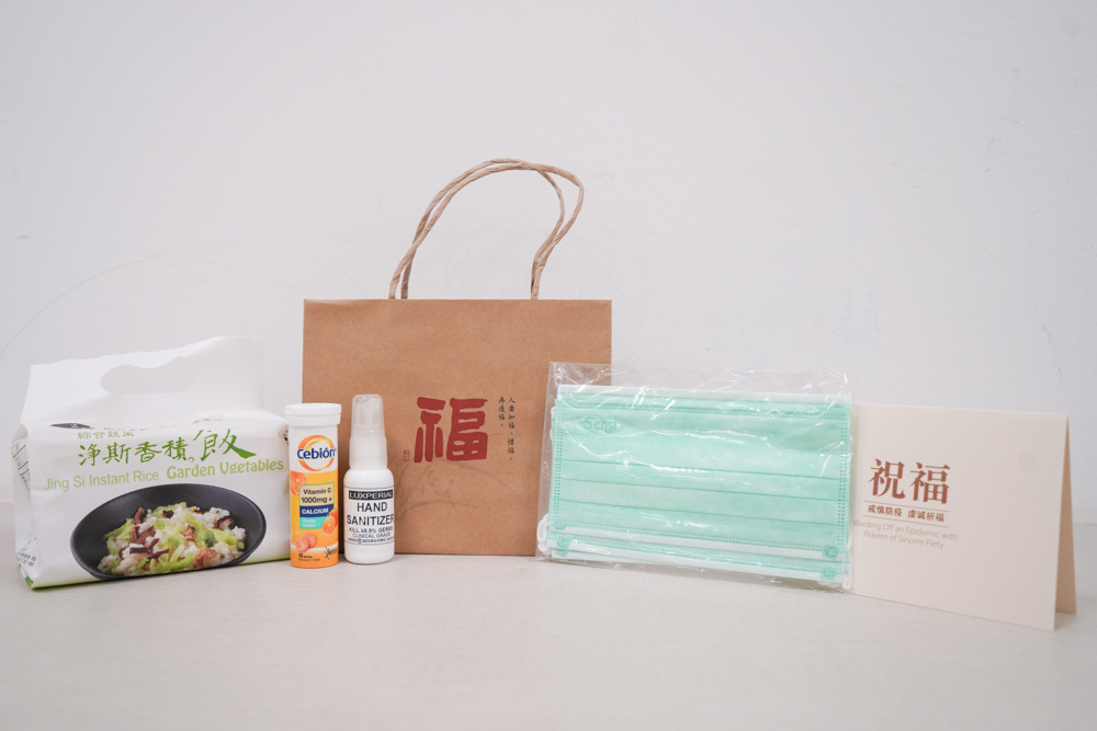 Inside the gift pack, there are four face masks, a packet of instant rice, a bottle of vitamin C, a bottle of hand sanitizer and a greeting card. (Photo by Chan May Ching)