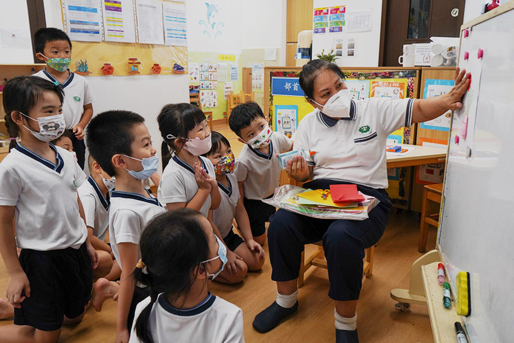 Xie Qiong Mei (right) explains to the children how to make a greeting card for parents. (Photo by Chan May Ching)